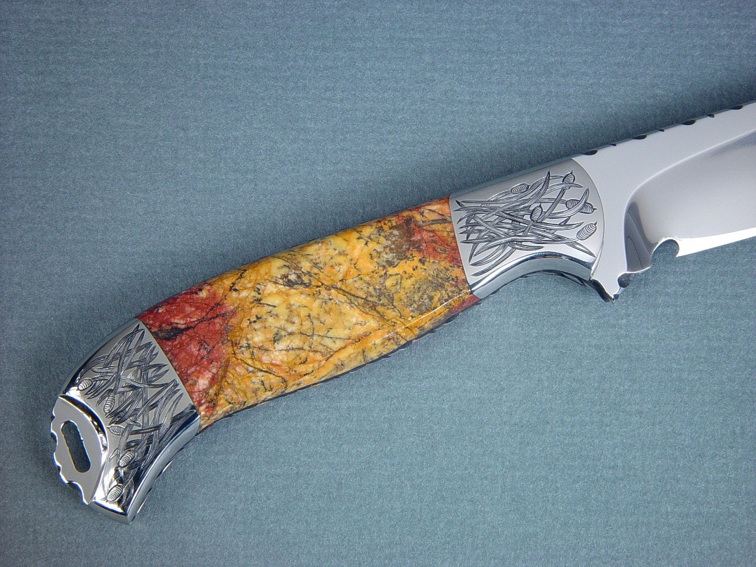 "Izar" obverse side view, knife in 440C high chromium stainless steel blade, hand-engraved 304 stainless steel bolsters, Sunset Jasper gemstone handle, hand-carved leather sheath