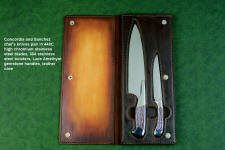 Concordia and Sanchez Chef's knives, obverse side view in T3 cryogenically treated 440C high chromium stainless steel blades, 304 stainless steel bolsters, Lace Amethyst gemstone handles, leather book case with top grain cover