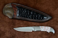 "Lacerta" fine handmade knife, obverse side view in CPM154CM powder metal technology stainless steel blade, 304 stainless steel bolsters, Red Freckled Dolomite gemstone handle, hand-carved leather sheath inlaid with Caiman skin